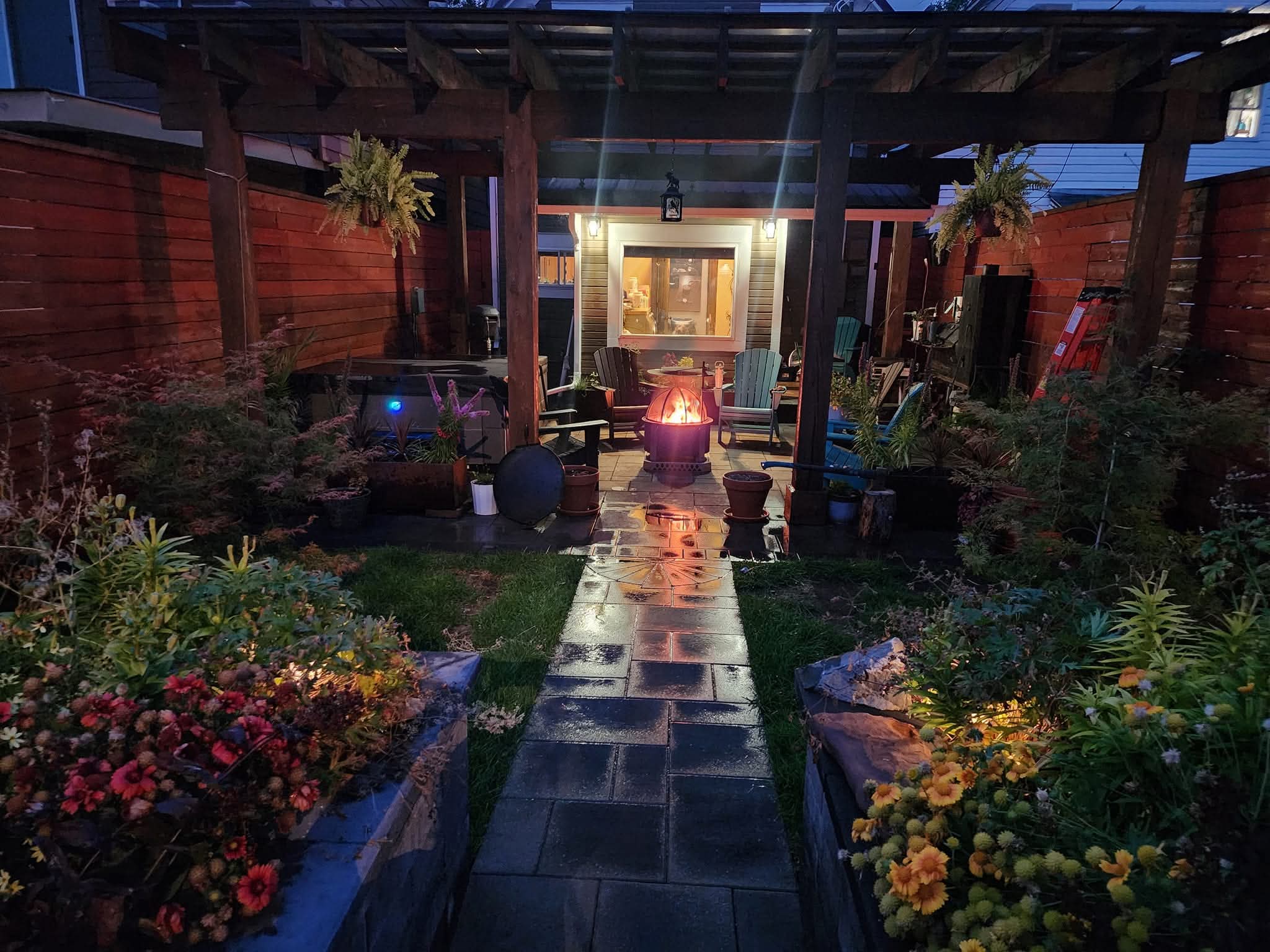 Outdoor design space with stone walkway, plants, warm lighting, wood privacy wall with pergola in Great Falls, MT